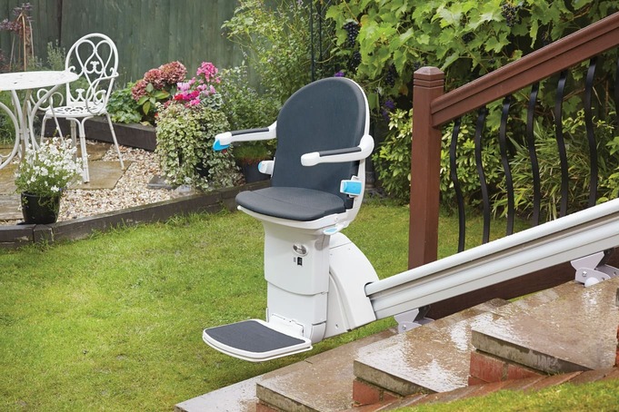 Ein Treppenlift, der an einer Treppe draußen zum Garten montiert ist.